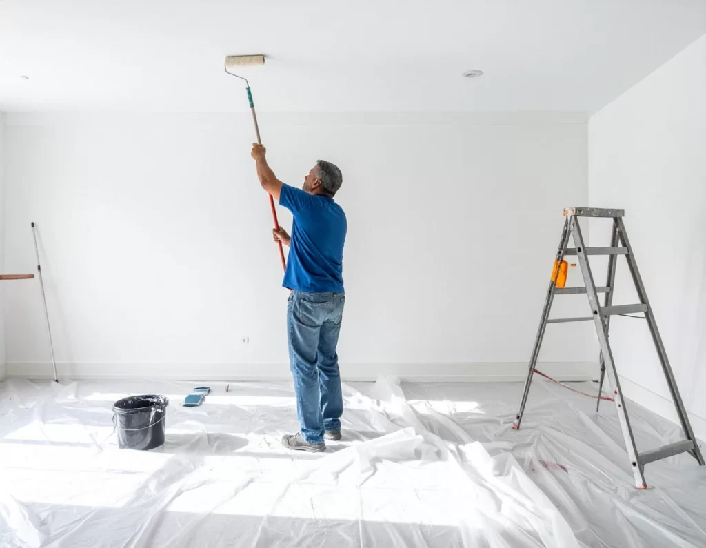 Applying primer to smooth ceiling with roller after popcorn ceiling removal.